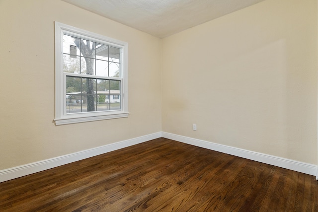 unfurnished room featuring baseboards and dark wood-style floors