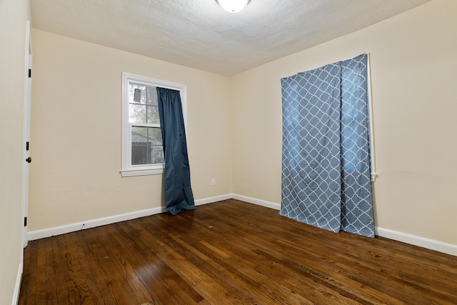 empty room with baseboards, dark wood-style flooring, and a textured ceiling