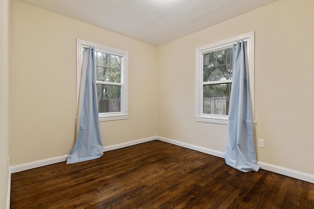 unfurnished room with baseboards and dark wood-style floors