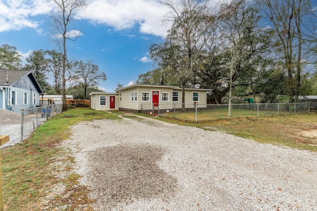 manufactured / mobile home with a fenced front yard, a front lawn, an outbuilding, and driveway