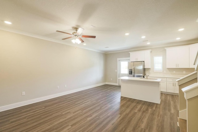 kitchen featuring a center island with sink, baseboards, dark wood finished floors, ornamental molding, and stainless steel refrigerator with ice dispenser