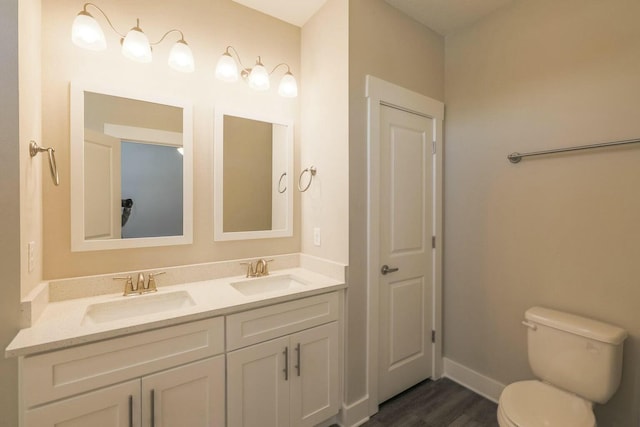 bathroom with double vanity, toilet, baseboards, and a sink