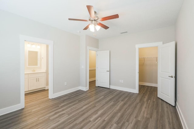 unfurnished bedroom featuring visible vents, wood finished floors, a closet, baseboards, and a spacious closet