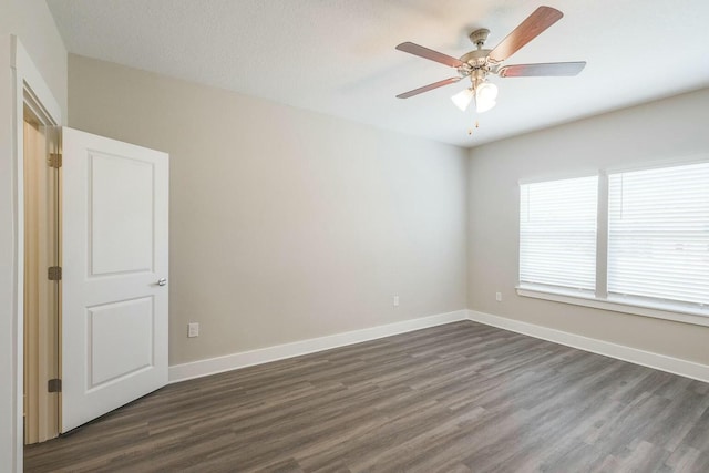 empty room featuring dark wood-type flooring, baseboards, and ceiling fan