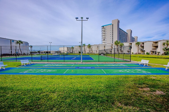 view of home's community with a lawn, a tennis court, and fence