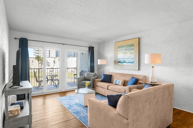 living room with a textured ceiling, wood finished floors, and a textured wall