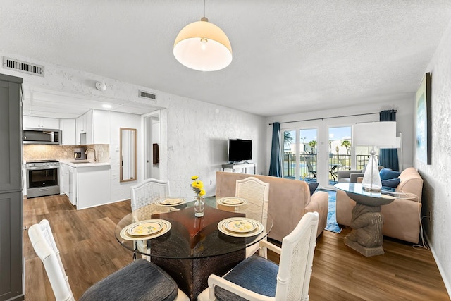 dining area with wood finished floors, visible vents, and a textured wall