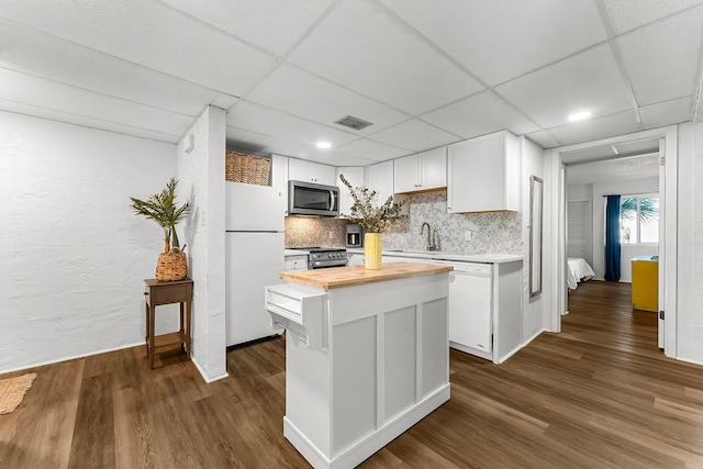 kitchen with butcher block countertops, backsplash, stainless steel appliances, white cabinets, and dark wood-style flooring