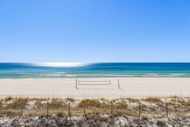 water view featuring fence and a beach view