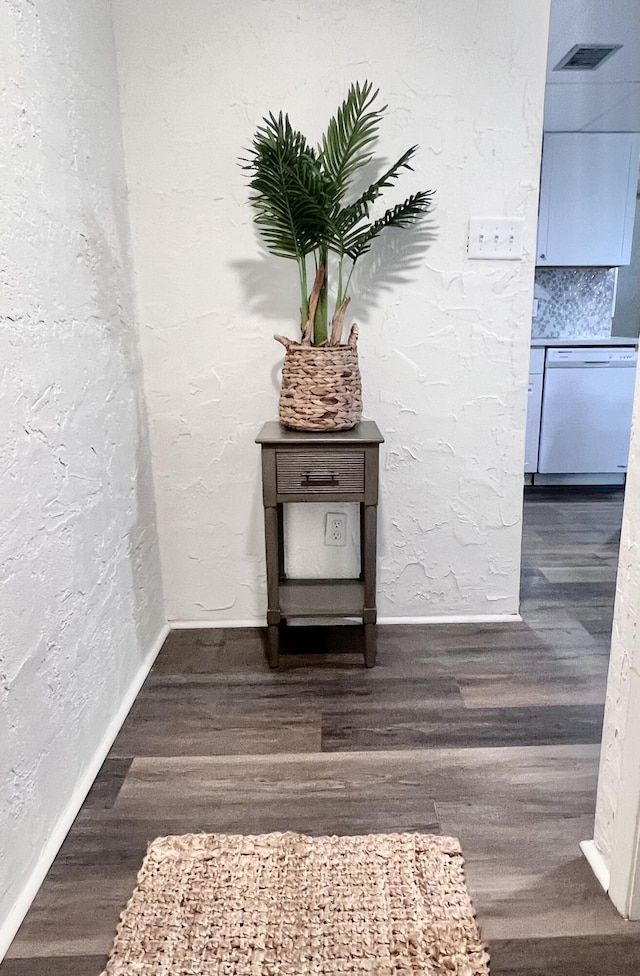 room details with visible vents, wood finished floors, baseboards, dishwasher, and a textured wall