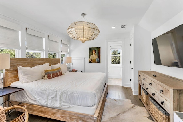 bedroom with visible vents, baseboards, recessed lighting, an inviting chandelier, and wood finished floors