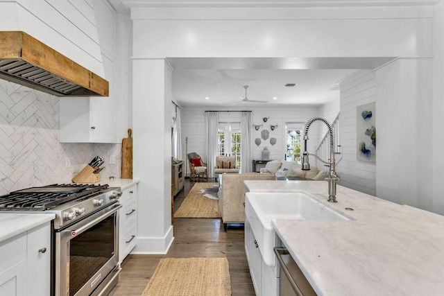 kitchen featuring custom range hood, tasteful backsplash, dark wood-style floors, white cabinets, and stainless steel gas range