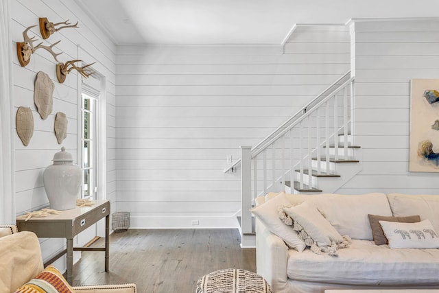 living area with stairs, hardwood / wood-style flooring, baseboards, and wood walls