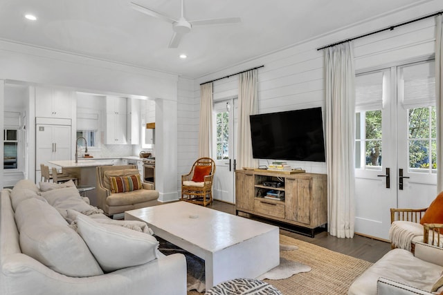 living room featuring dark wood finished floors, a healthy amount of sunlight, crown molding, and ceiling fan