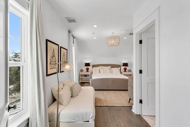 bedroom featuring a notable chandelier, recessed lighting, wood finished floors, and visible vents