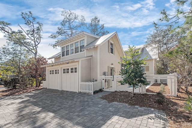 view of home's exterior with a gate, an attached garage, a fenced front yard, decorative driveway, and metal roof