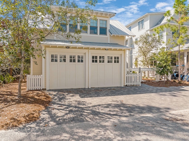 garage with decorative driveway and fence