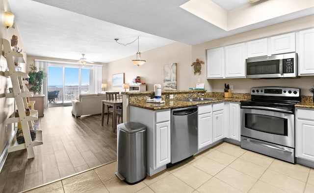 kitchen with white cabinetry, a peninsula, dark stone counters, and stainless steel appliances