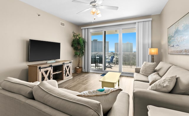 living area with visible vents, baseboards, wood finished floors, and a ceiling fan