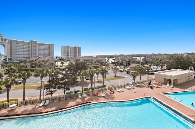 community pool featuring a patio area, a city view, and fence