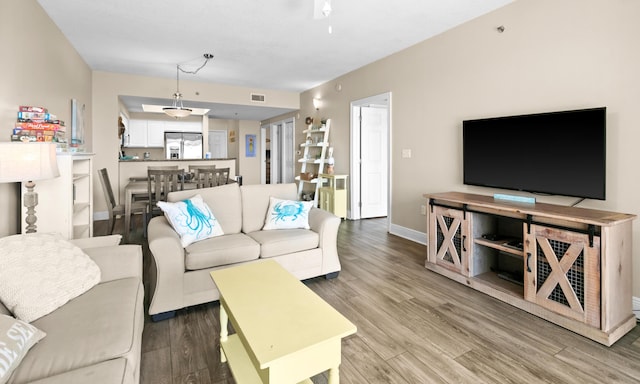 living area with visible vents, baseboards, and wood finished floors