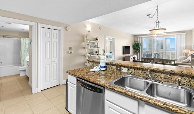 kitchen featuring light tile patterned floors, a sink, hanging light fixtures, stainless steel dishwasher, and open floor plan