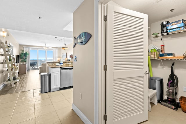 kitchen featuring a ceiling fan, light stone counters, light tile patterned flooring, baseboards, and dishwasher