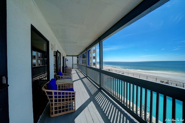 balcony featuring a view of the beach and a water view