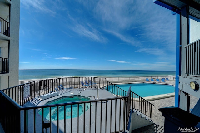 view of pool featuring a hot tub and a water view