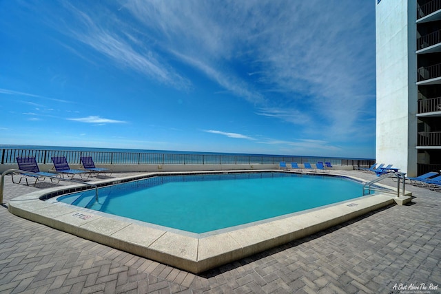 community pool with a patio area and a water view