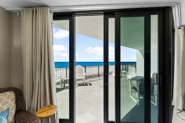 doorway with floor to ceiling windows, a healthy amount of sunlight, and a water view