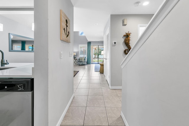 hallway with light tile patterned floors, baseboards, and a sink