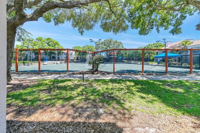 surrounding community with a tennis court, fence, and a lawn