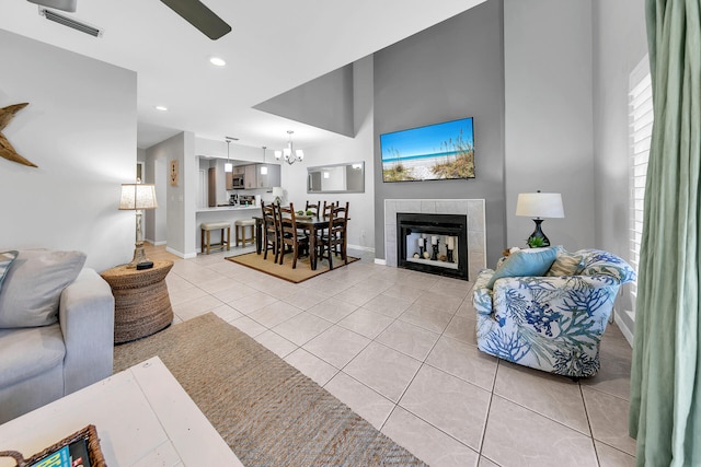 living room featuring light tile patterned floors, baseboards, recessed lighting, a tiled fireplace, and ceiling fan with notable chandelier