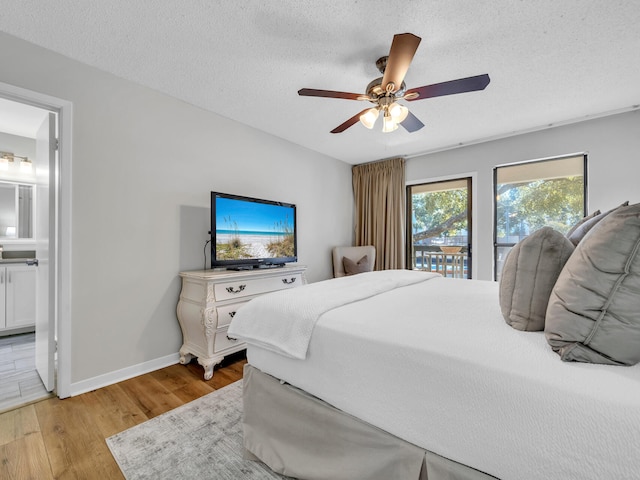 bedroom featuring connected bathroom, baseboards, light wood-style floors, a textured ceiling, and a ceiling fan