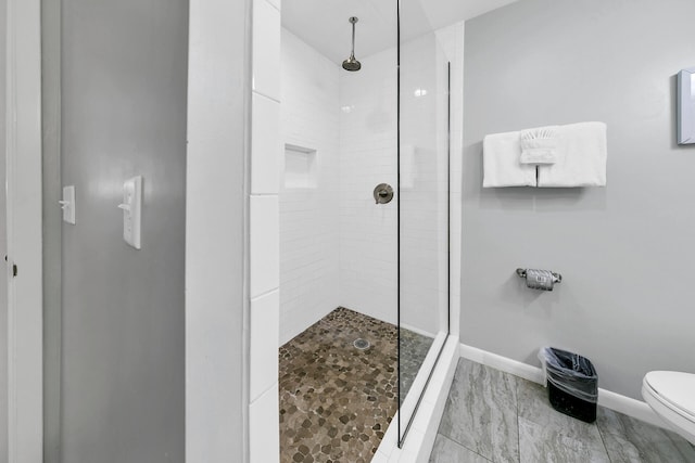 full bathroom with baseboards, toilet, and a tile shower