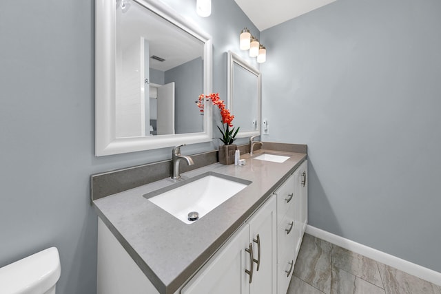 bathroom featuring double vanity, toilet, visible vents, and a sink