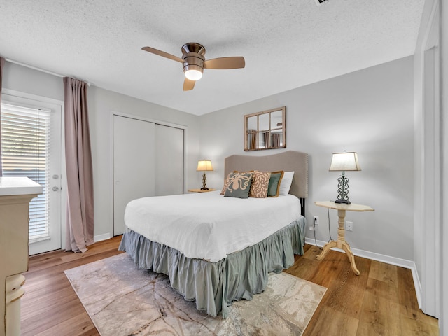 bedroom featuring light wood finished floors, baseboards, ceiling fan, a closet, and a textured ceiling