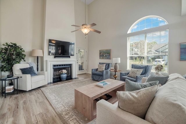 living room with a ceiling fan, plenty of natural light, wood finished floors, and a fireplace with flush hearth