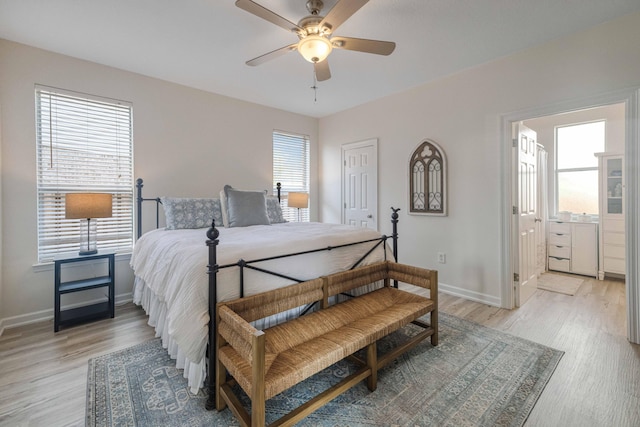 bedroom featuring baseboards, ensuite bathroom, and light wood-style floors