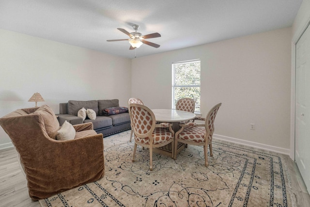 dining space featuring a ceiling fan, baseboards, and wood finished floors