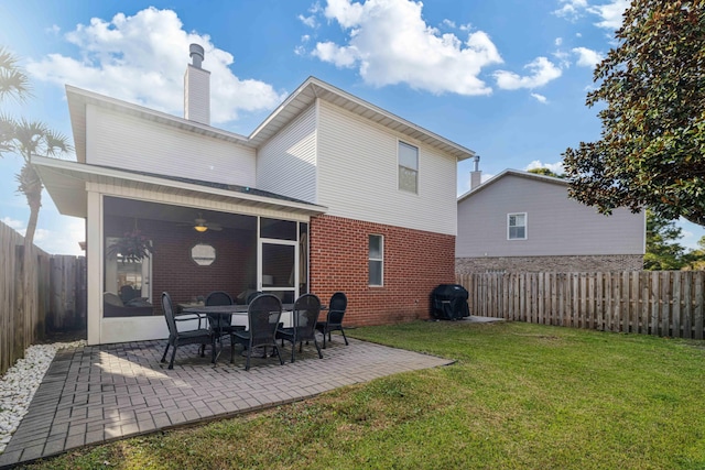 back of property featuring a yard, a fenced backyard, a sunroom, a chimney, and a patio area