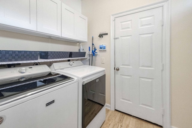 laundry room with cabinet space, washing machine and dryer, and light wood finished floors