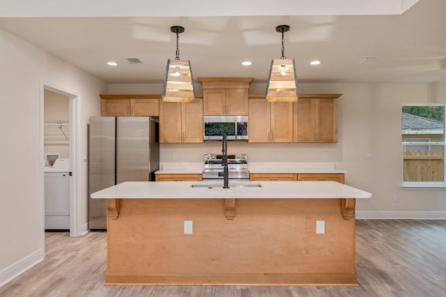 kitchen featuring visible vents, washer / clothes dryer, an island with sink, stainless steel appliances, and light countertops