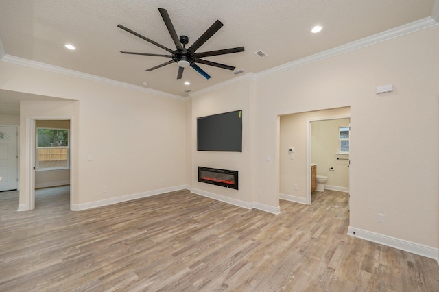 unfurnished living room with baseboards, a glass covered fireplace, crown molding, and light wood finished floors