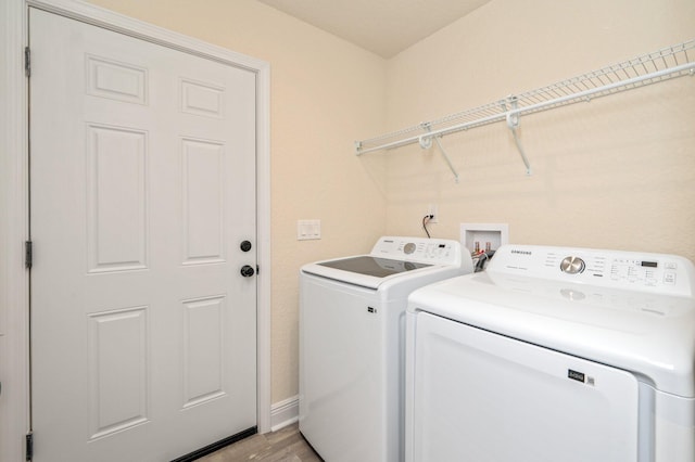 laundry area featuring laundry area, washing machine and dryer, light wood-type flooring, and baseboards