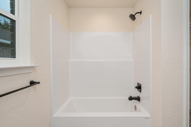 bathroom with shower / tub combination and a textured wall