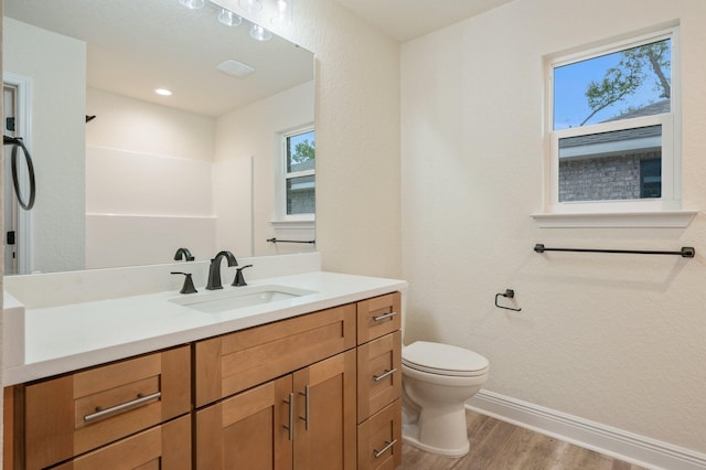 bathroom featuring visible vents, baseboards, toilet, wood finished floors, and vanity