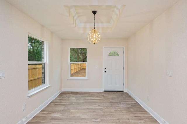 foyer with baseboards, light wood-style floors, and a chandelier