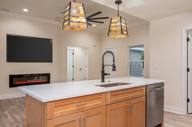 kitchen with crown molding, open floor plan, stainless steel dishwasher, a glass covered fireplace, and a sink